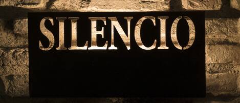 A sign with the word "SILENCIO" mounted on a stone wall.