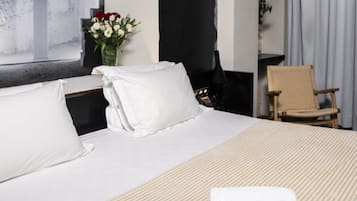 Ein Hotelzimmer mit einem großen Bett, einem schwarz-weißen abstrakten Gemälde an der Wand, einer Vase mit Blumen und einem Sessel.
