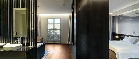Una camera d'albergo moderna con un letto grande, un bagno con un lavabo e vista sulla città dalla finestra.
