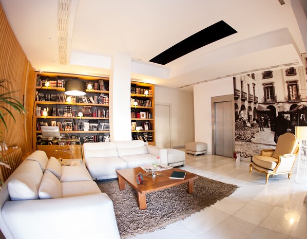 Una sala de estar moderna con un sofá blanco, una mesa de centro de madera y una estantería grande llena de libros.
