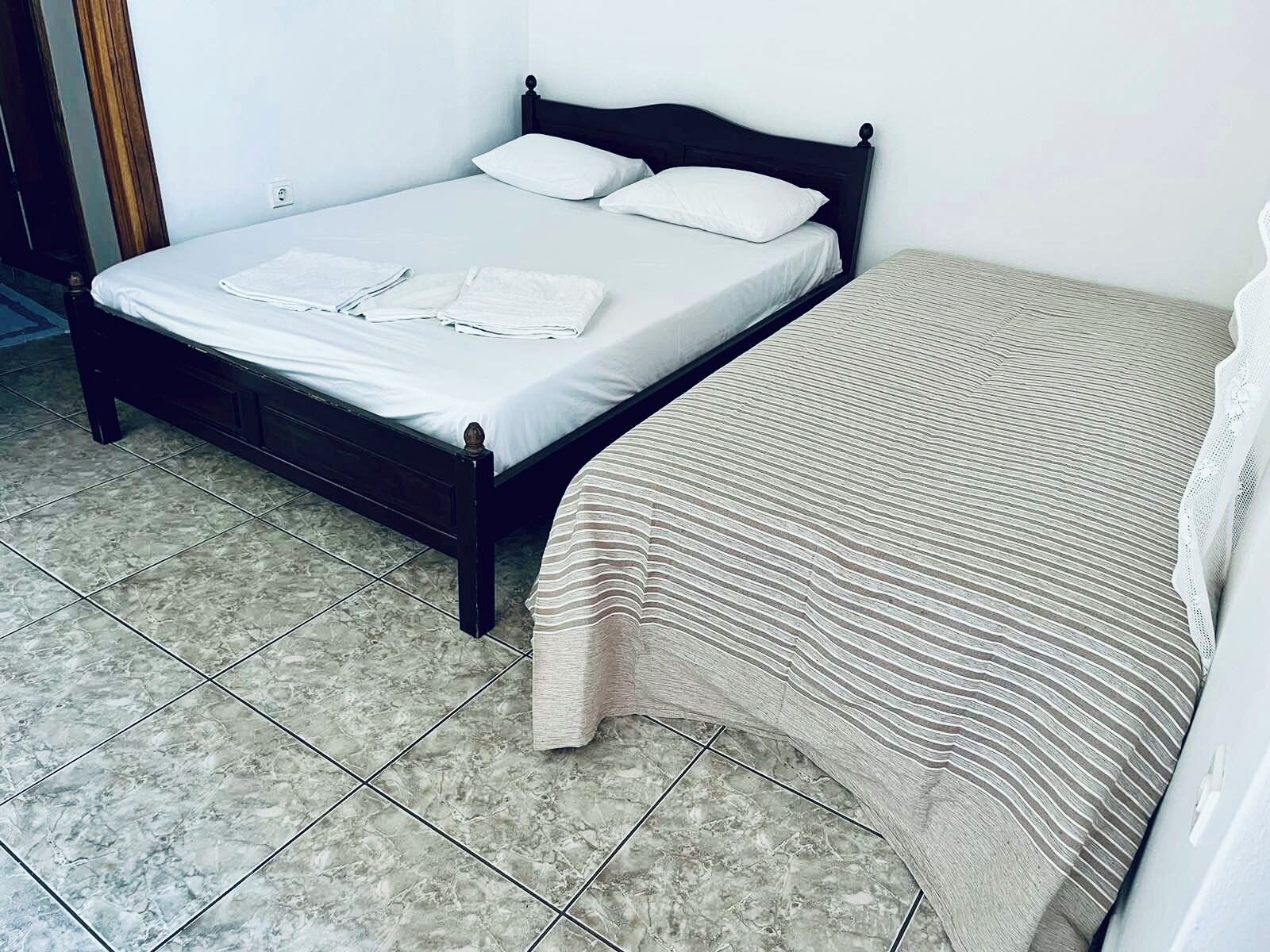A bed with white linens, a dark wooden headboard, and a striped blanket.