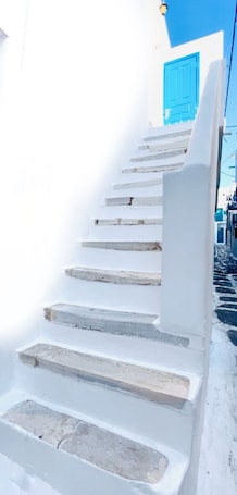 A white staircase leading to a blue door, with a clear sky in the background.