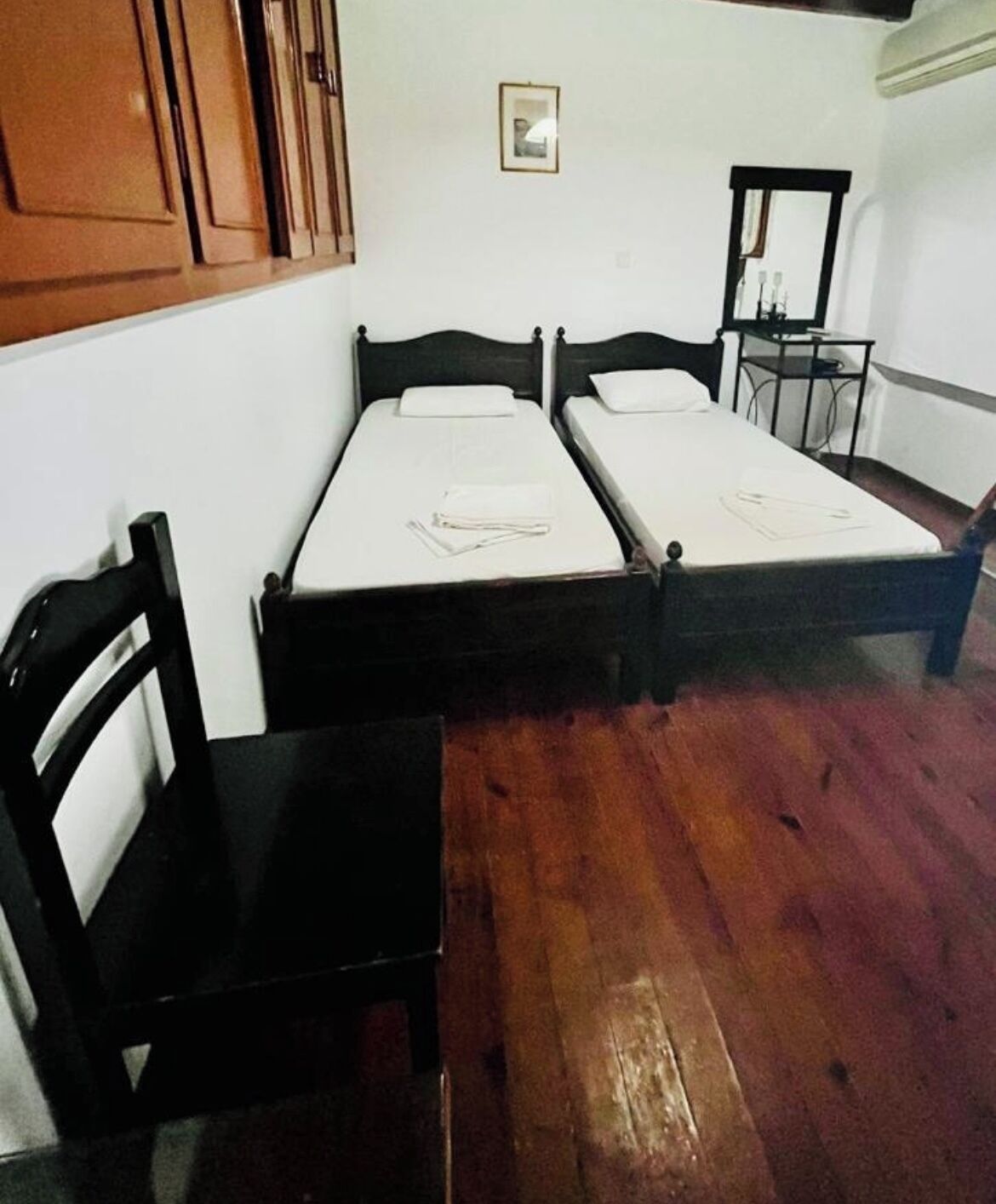A room with two single beds, a wooden chair, and a small table.