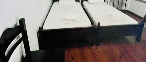 A room with two single beds, a wooden chair, and a small table.