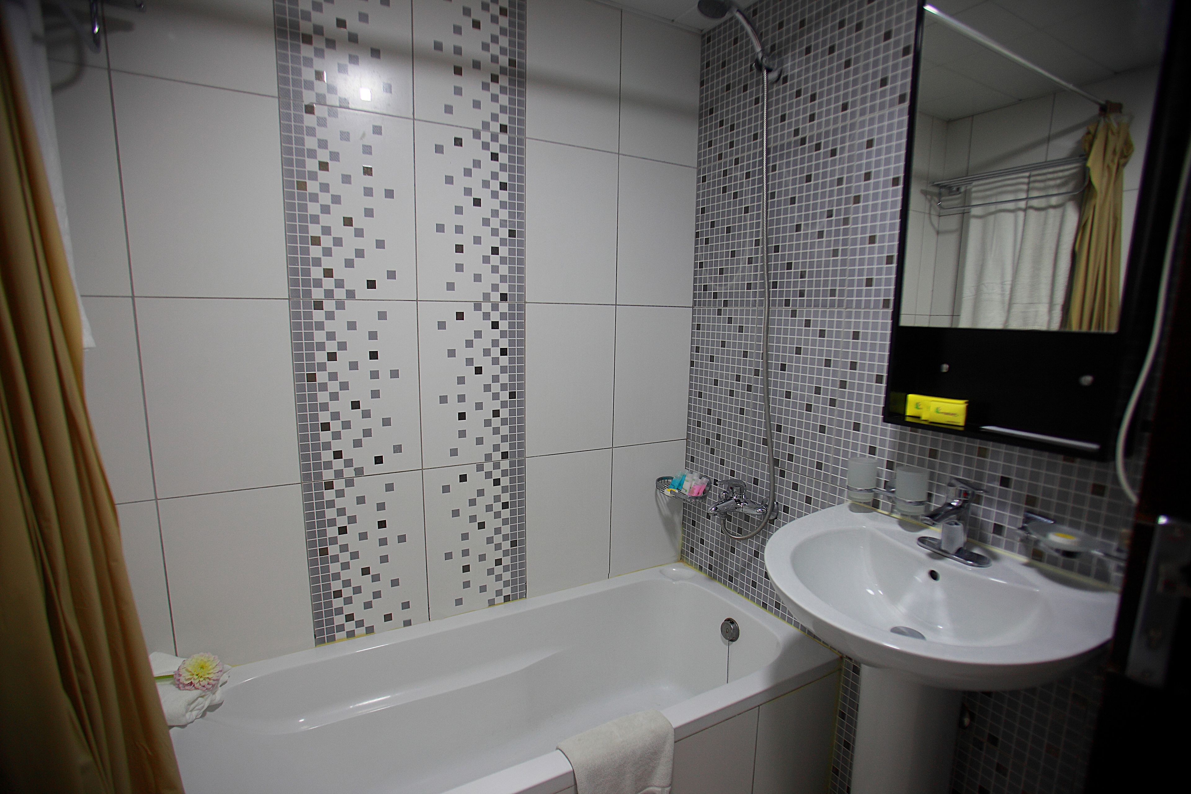 A bathroom with a bathtub, a sink, and a mirror.
