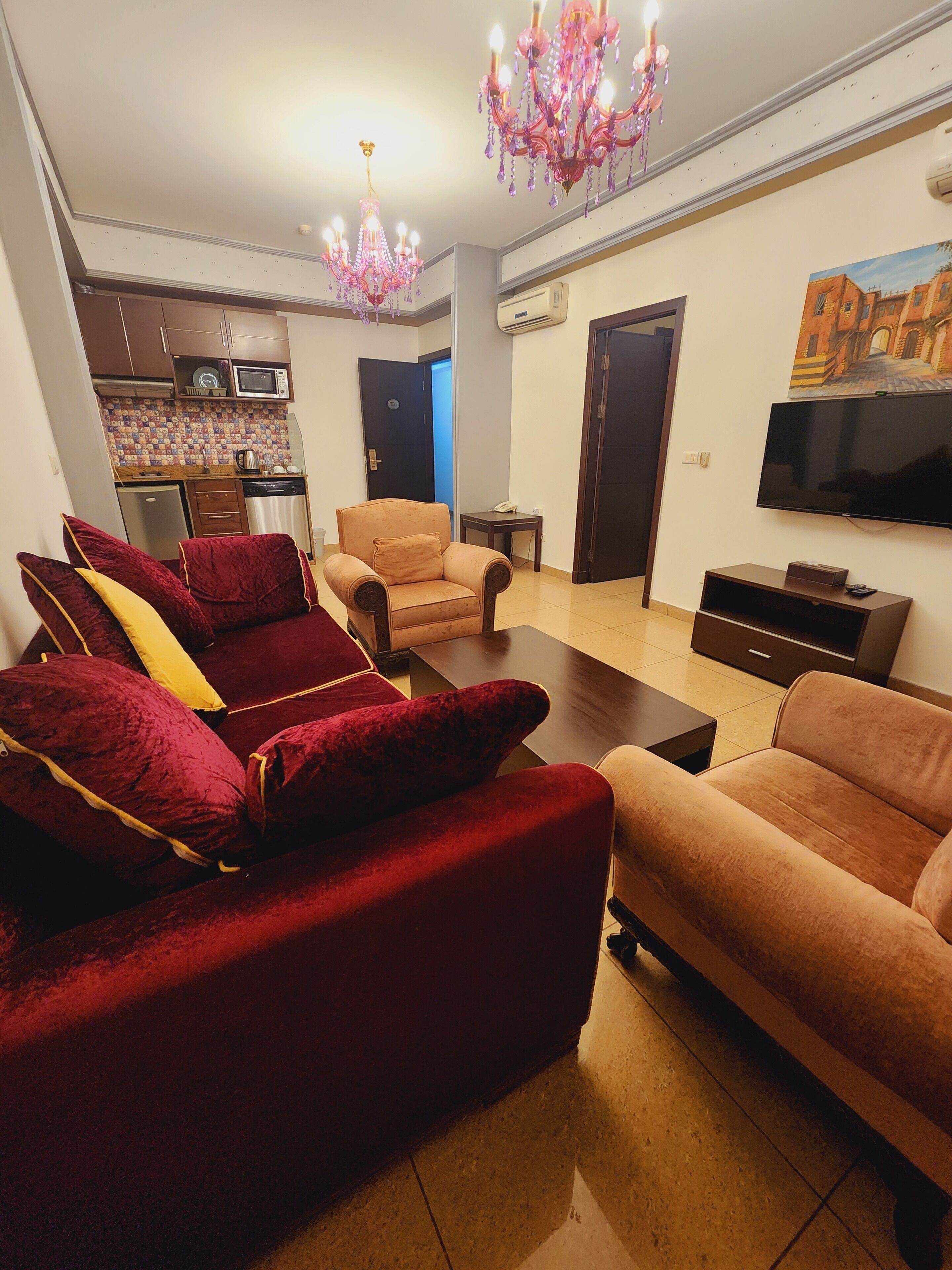 A living room with a sofa set, a television, and a chandelier.