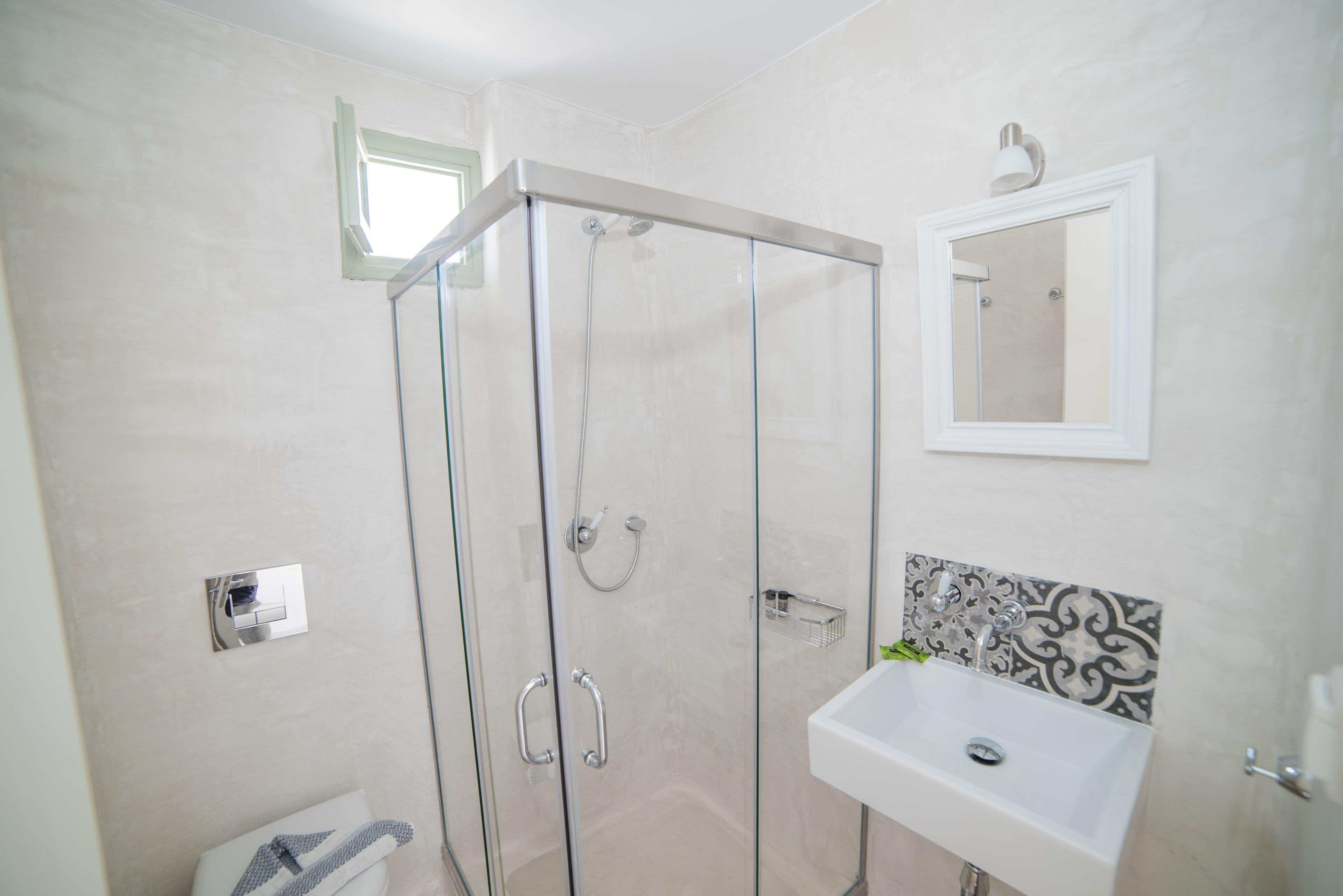 A modern bathroom with a glass-enclosed shower, a white sink, and a mirror above it.