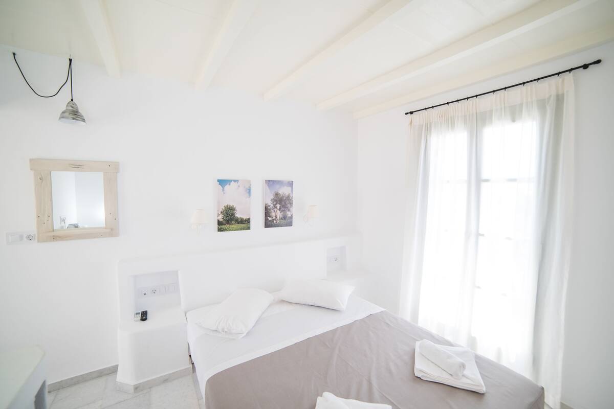 Une chambre d’hôtel avec un lit, une table de chevet, un miroir et deux tableaux encadrés au mur.