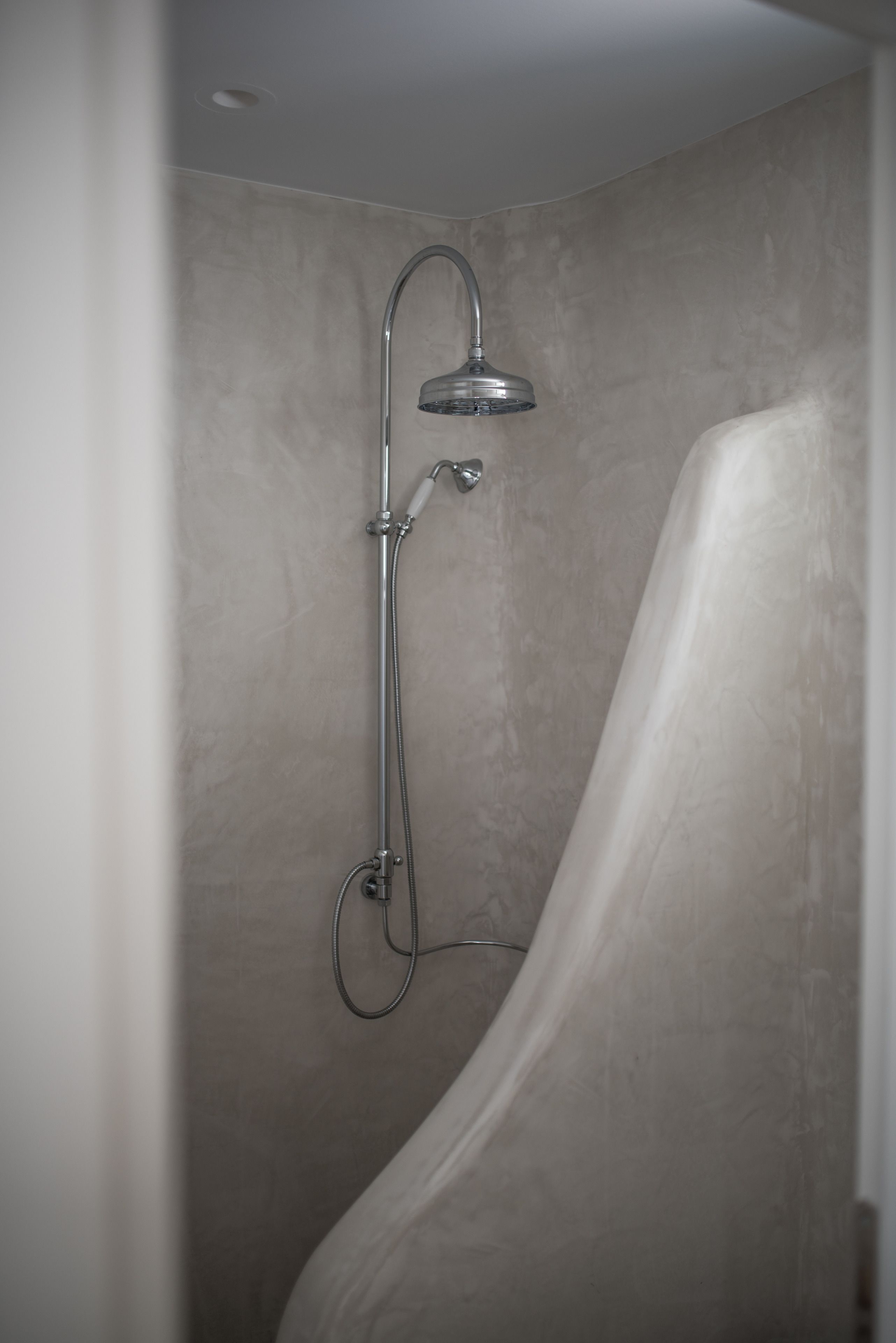Ducha con manguera curva y cabezal de ducha instalado en la pared.