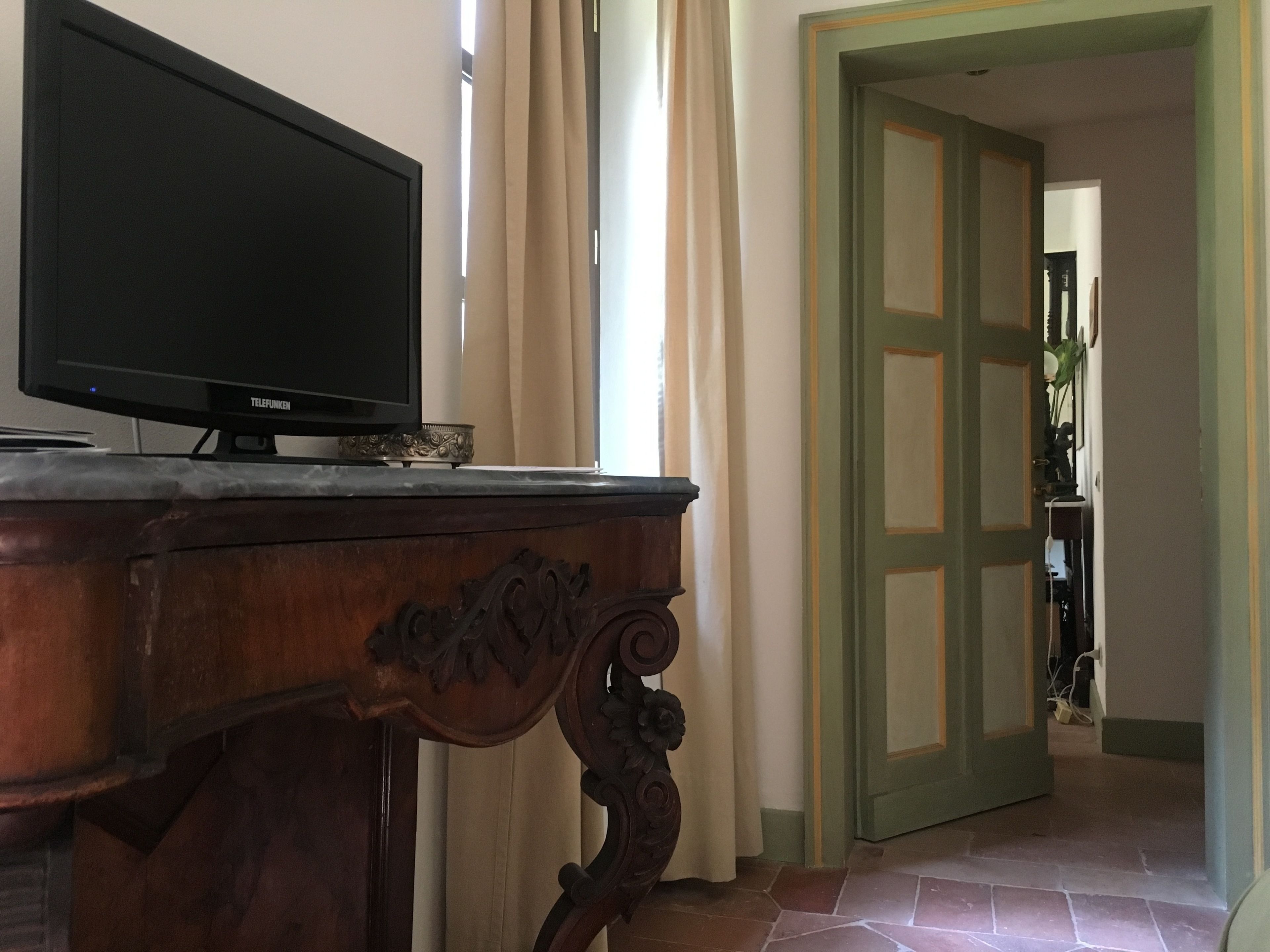 Ein Holzschrank mit einem Flachbildfernseher darauf, einer Dekoschale und einer Tür zu einem anderen Raum.