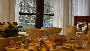 Taula de menjador amb diferents aliments i vista a arbres a través d'una finestra.