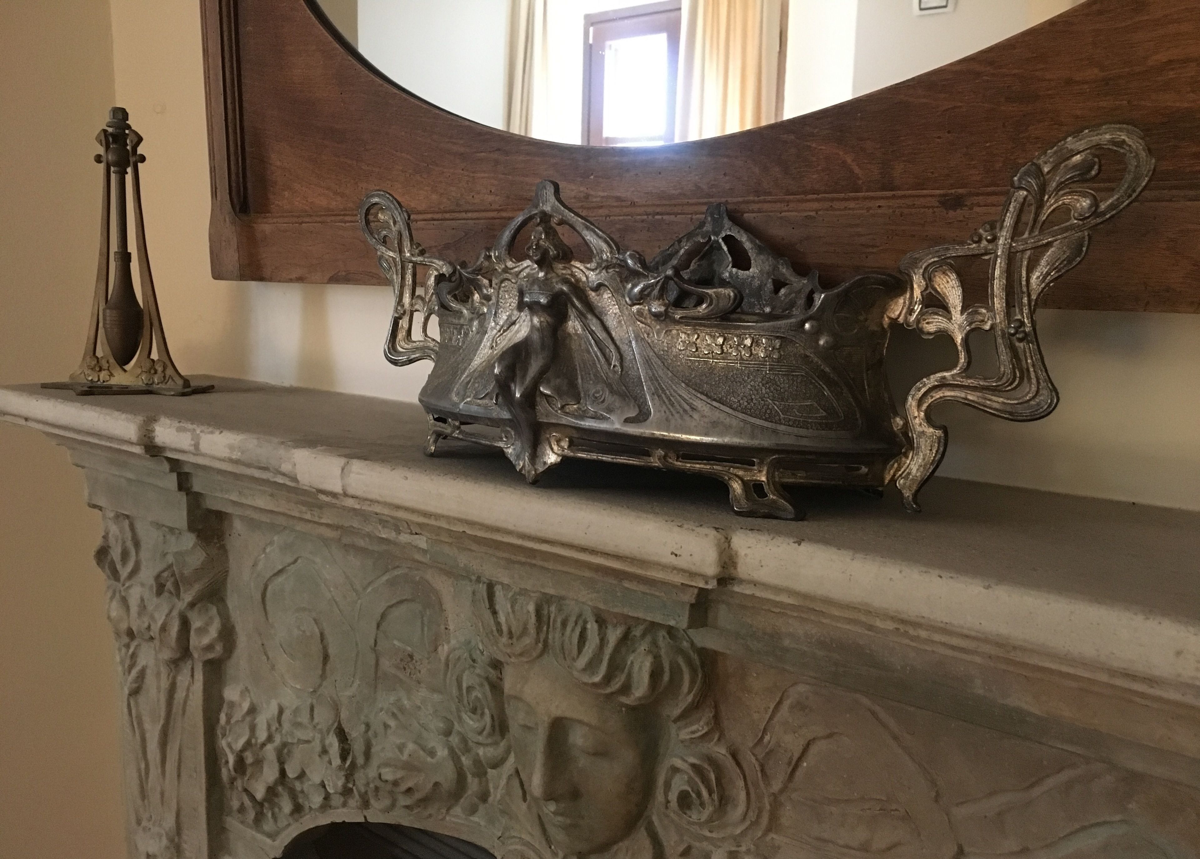 Une cheminée ornée de sculptures complexes et agrémentée d’un élément décoratif en métal sur le manteau.