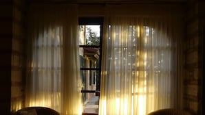 Habitació amb vistes per la finestra, cortines transparents, un sofà i una taula.