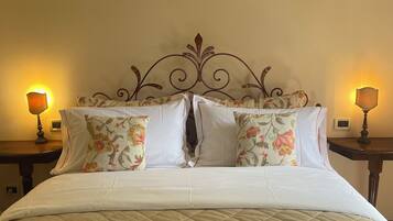 Una cama con cabecera estampada con motivos florales, dos mesitas de noche con lámparas y una colcha acolchada.
