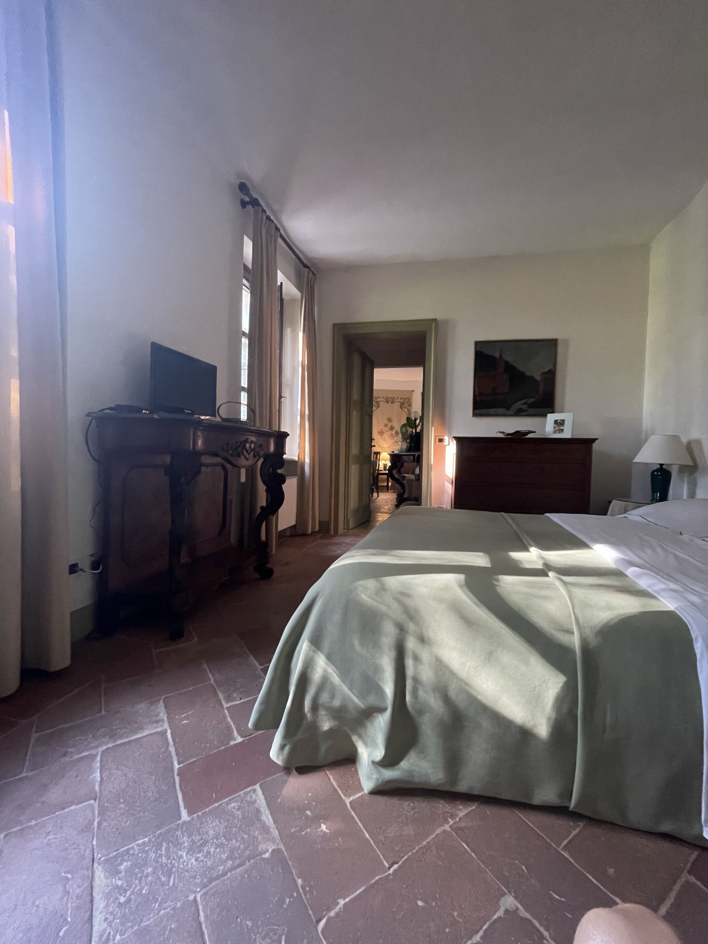 Una camera da letto con un letto, una scrivania, una cassettiera e un quadro appeso al muro.