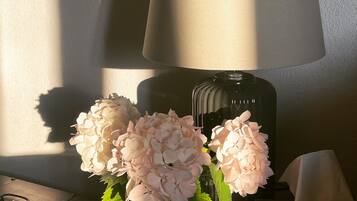 A lamp, a vase with flowers, and a tissue box on a table.