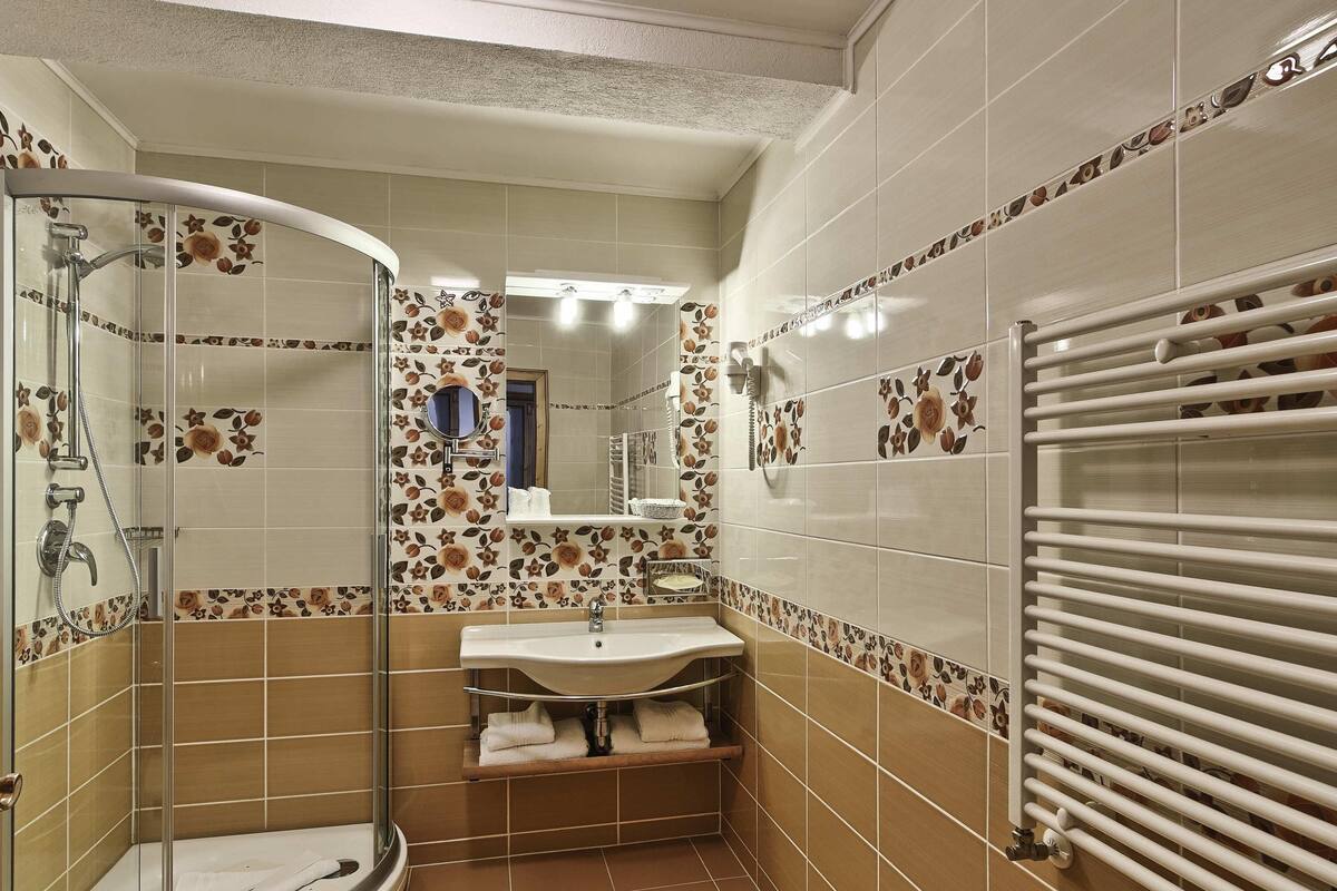 Une salle de bain avec une douche à parois de verre, un lavabo, un miroir et un porte-serviettes.