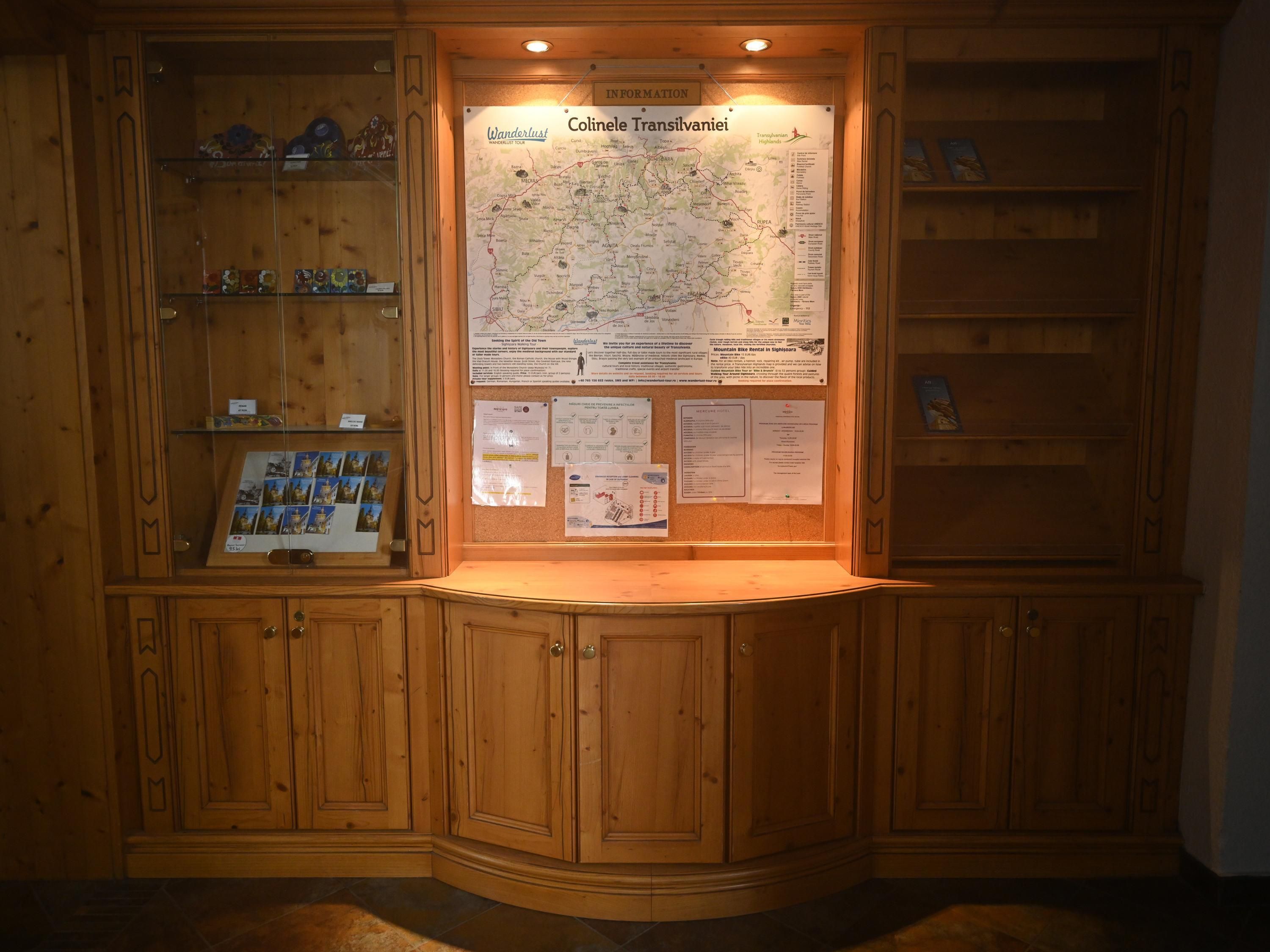 A wooden cabin with a map display, wooden shelves with souvenirs, and a corkboard with notices.