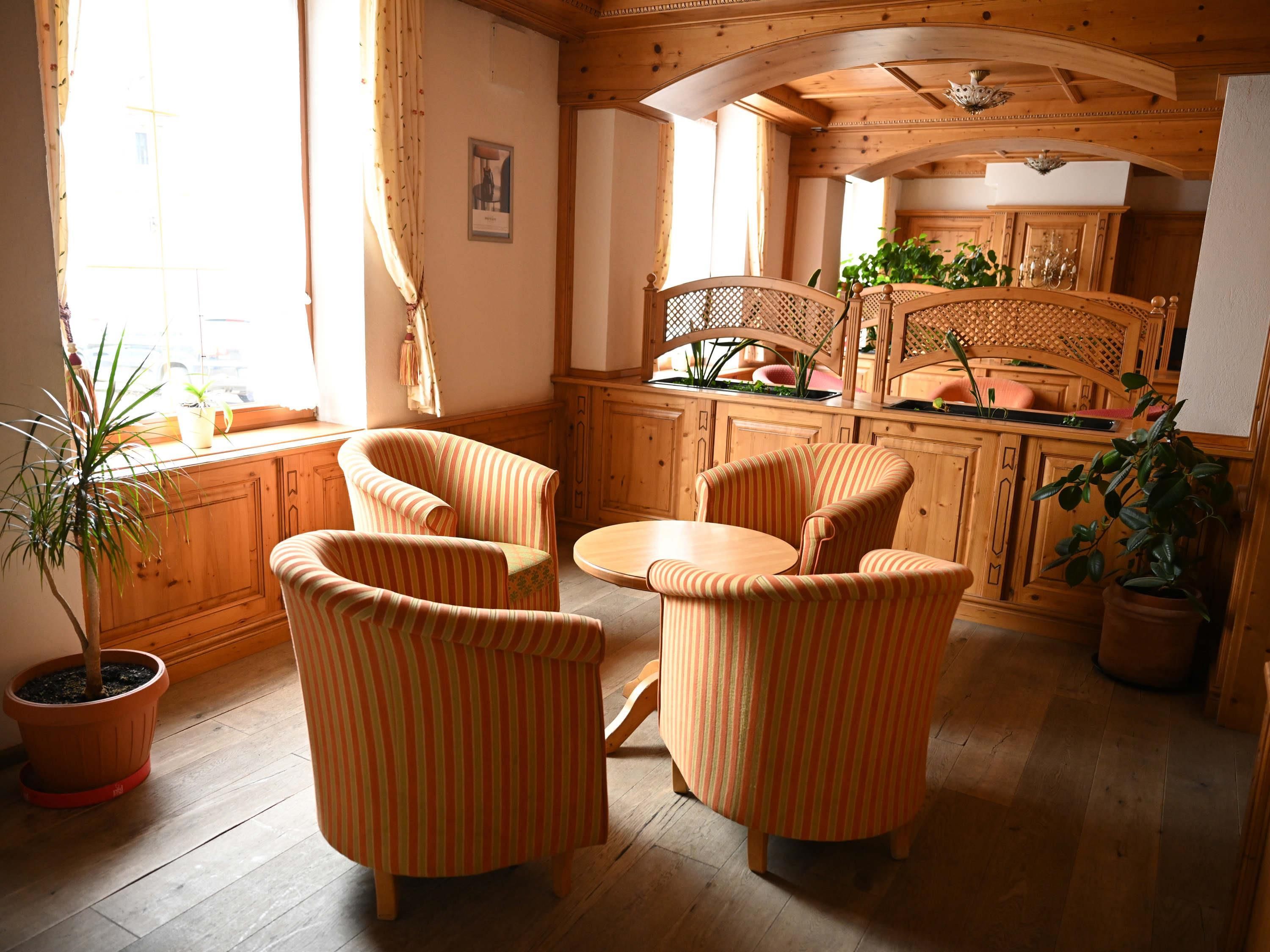 Un interior de madera con zona de comedor, sillas a rayas, una mesa y plantas en macetas.
