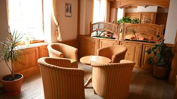 Un interior de madera con zona de comedor, sillas a rayas, una mesa y plantas en macetas.