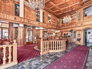 A spacious lobby with wooden paneling, a bar area, and a red carpeted floor.