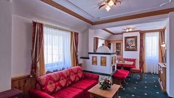 Une chambre d’hôtel avec un canapé rouge, une table à manger en bois et un petit coin cuisine.