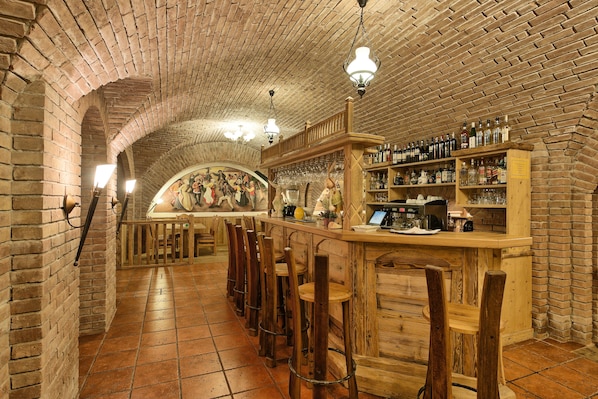 A bar area with brick walls, wooden bar stools, and shelves of bottles and glasses.