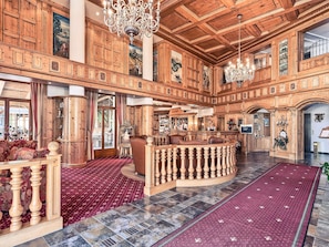 A spacious lobby with wooden paneling, a bar area, and a red carpeted floor.