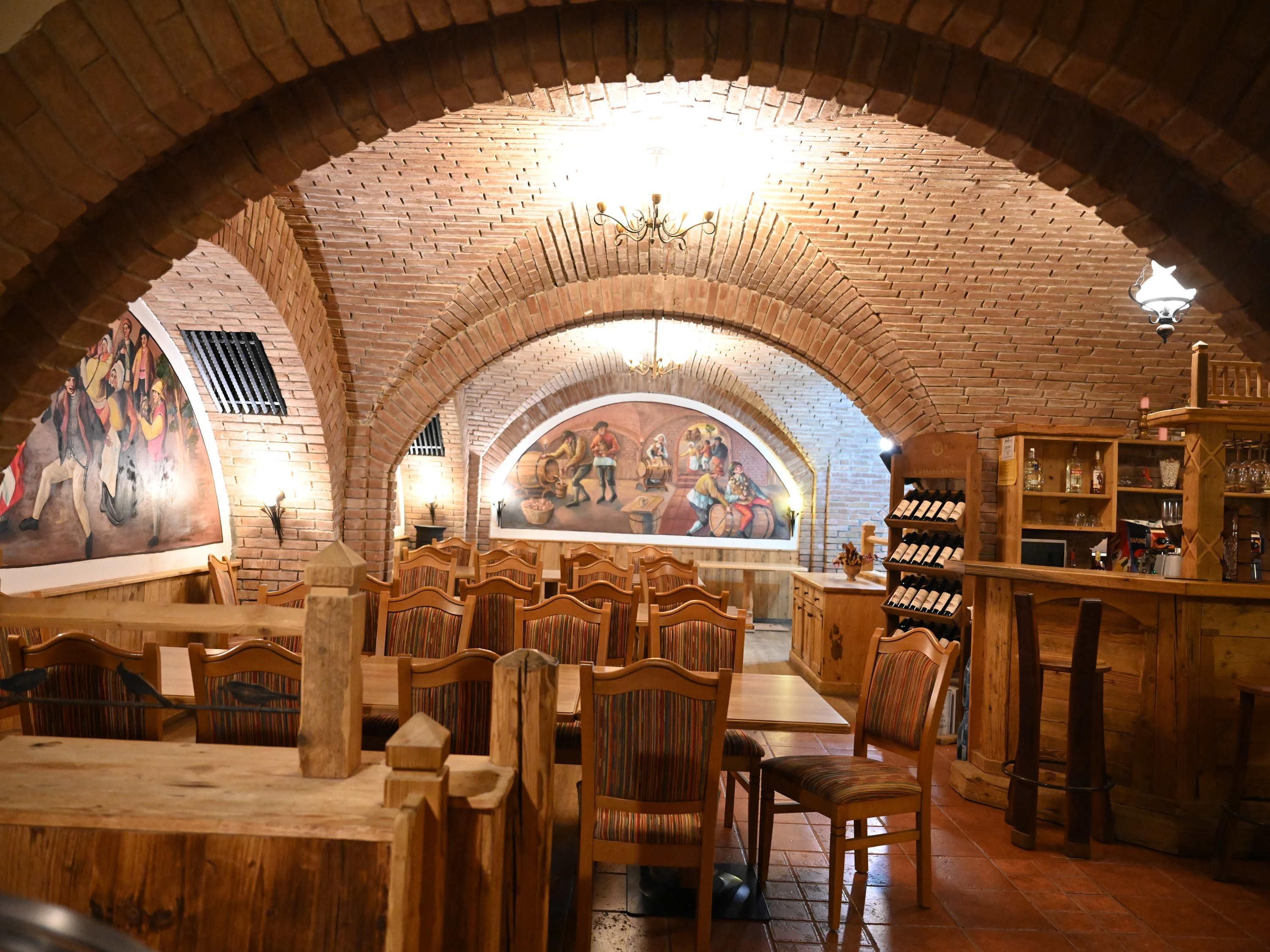 A restaurant with brick arches, wooden furniture, and a mural on the wall.