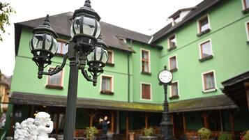 Un patio con edificios verdes, mesas al aire libre y un reloj.
