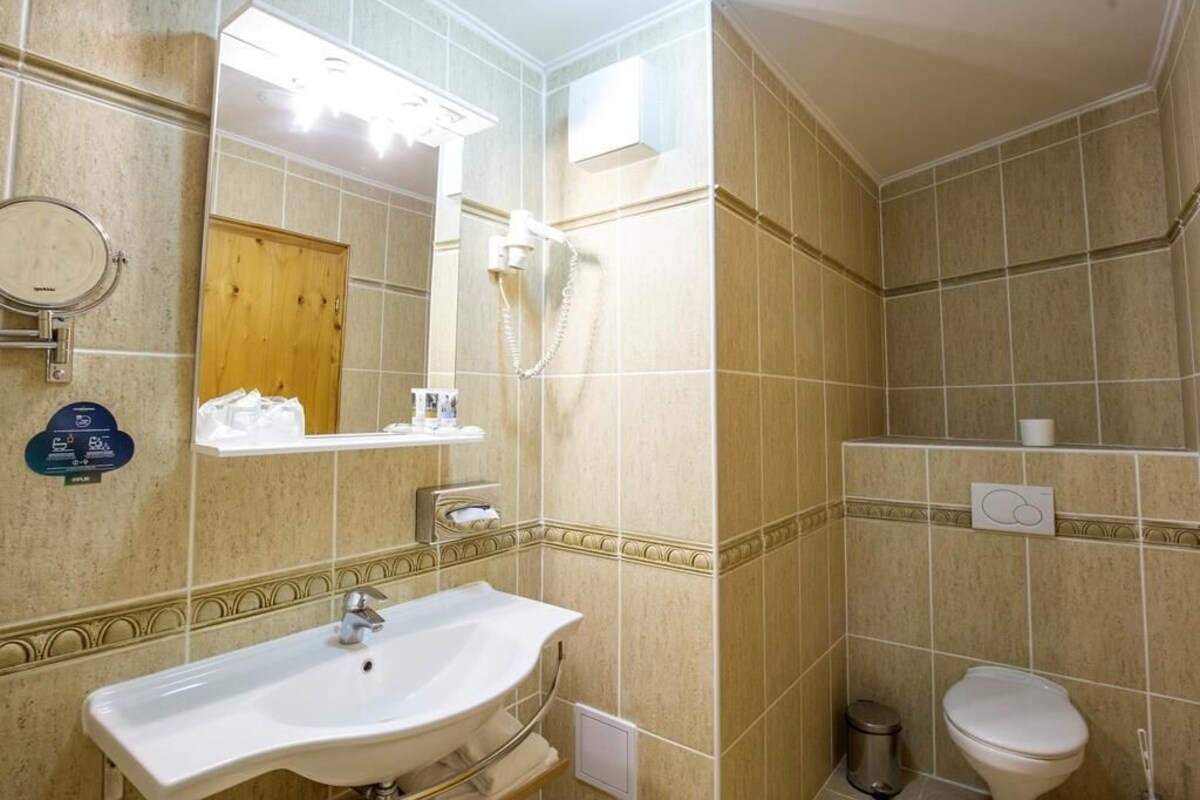 A bathroom with a sink, mirror, shower, toilet, and a towel rack.