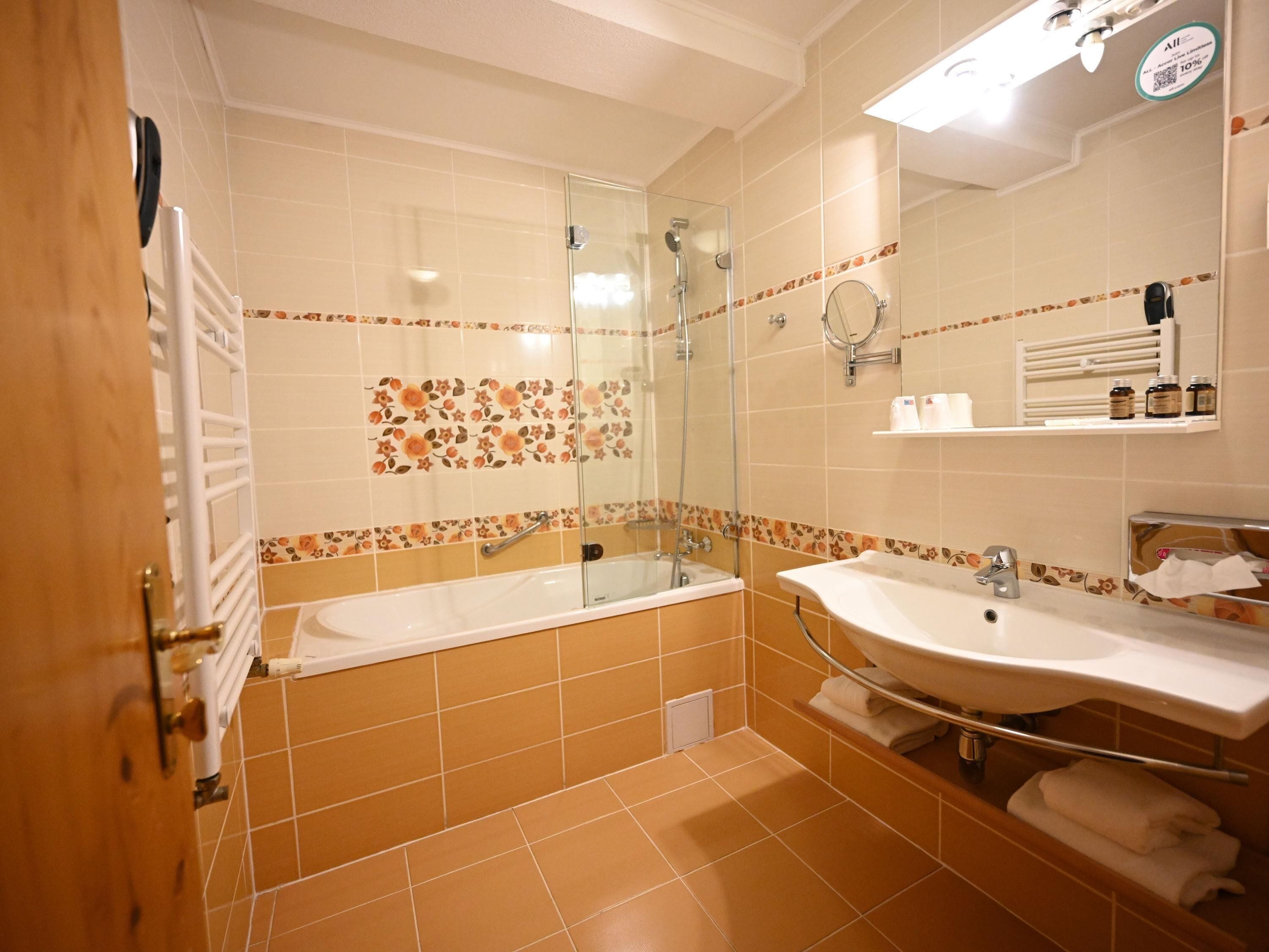 Un baño con bañera, ducha, lavamanos y espejo.