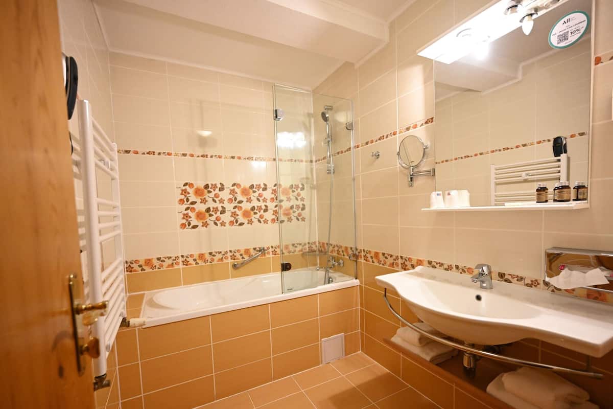 Une salle de bain avec une baignoire, une douche, un lavabo et un miroir.
