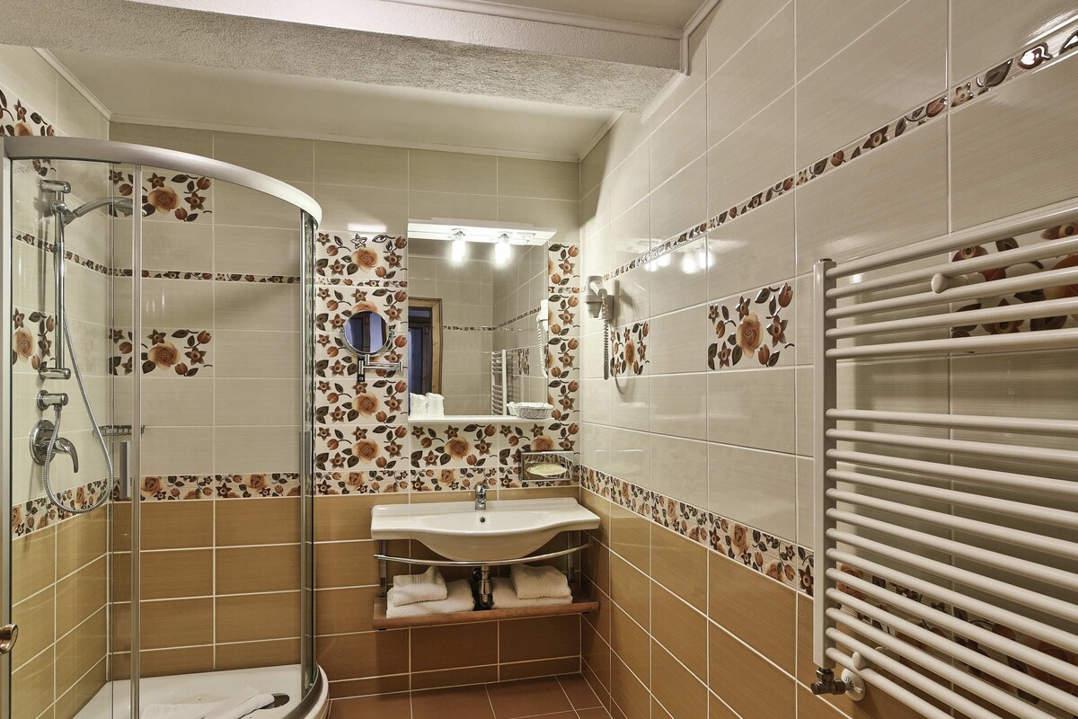 Une salle de bain avec une douche à parois de verre, un lavabo, un miroir et un porte-serviettes.