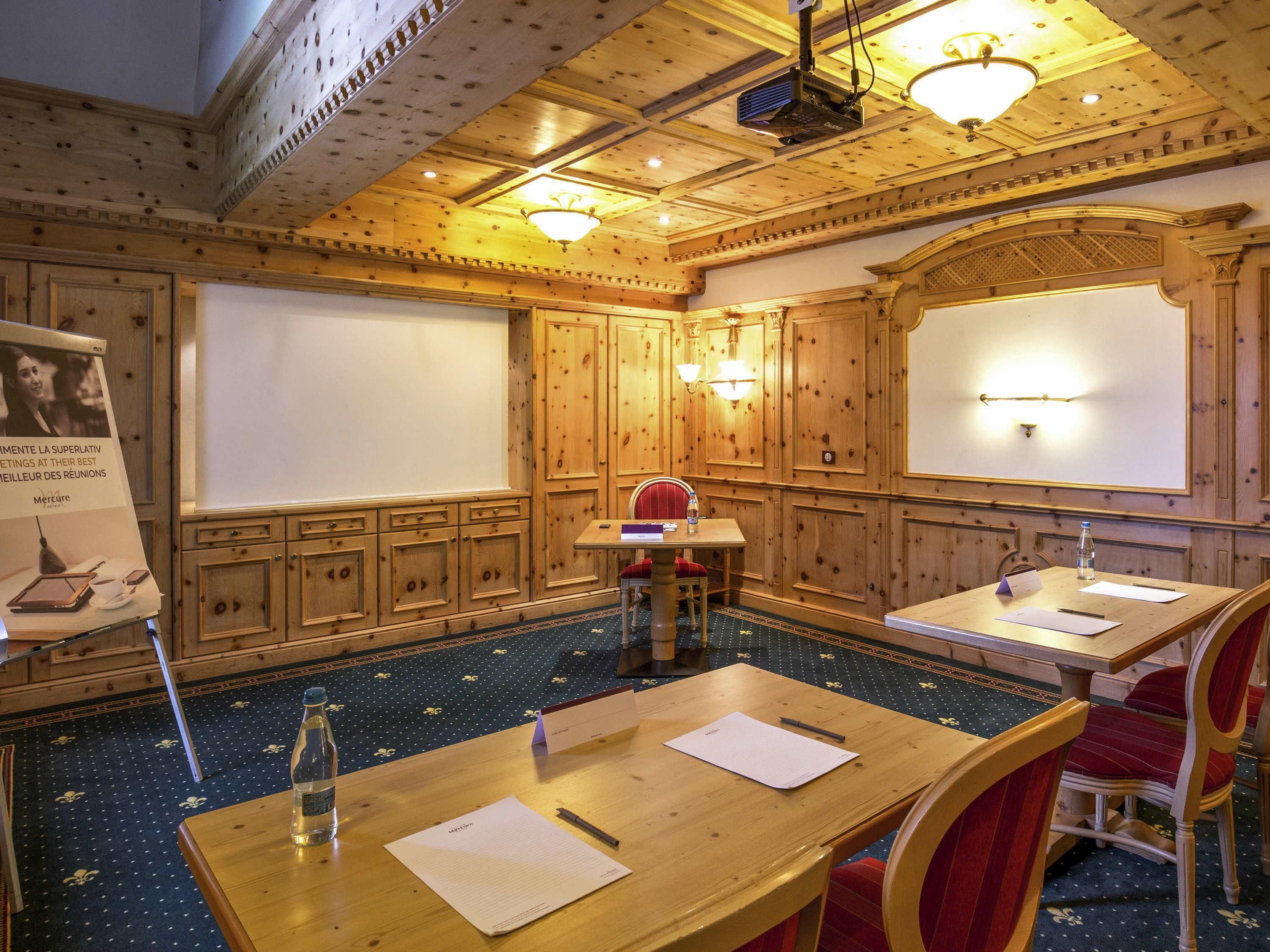A conference room with wooden paneling, a projector, and a large screen.