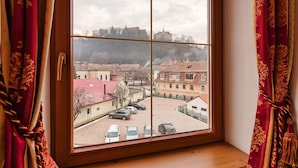 A room with a large window overlooking a courtyard with parked cars and buildings.