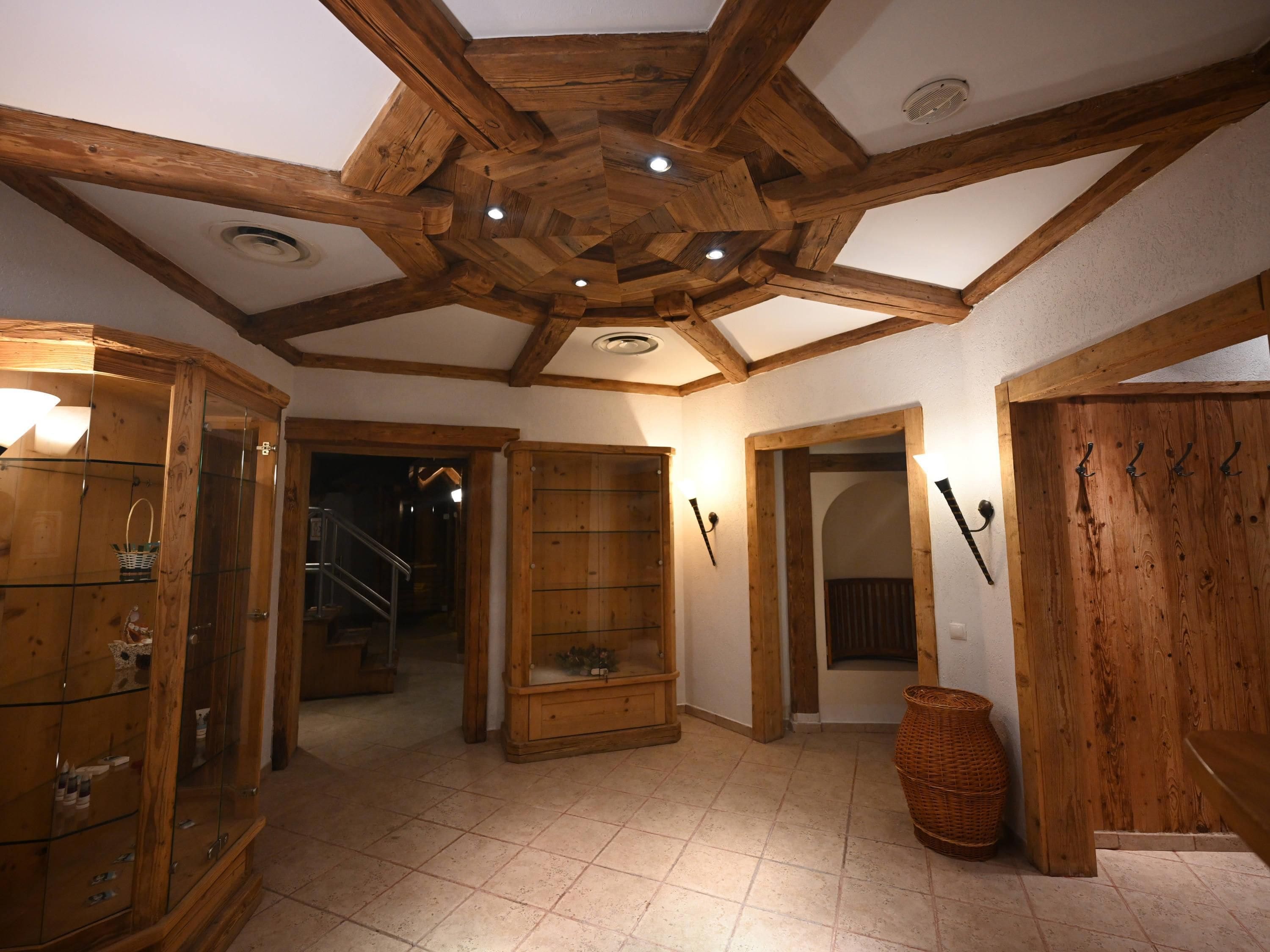 A wooden interior with a high ceiling, a staircase, and a wooden door with hooks.