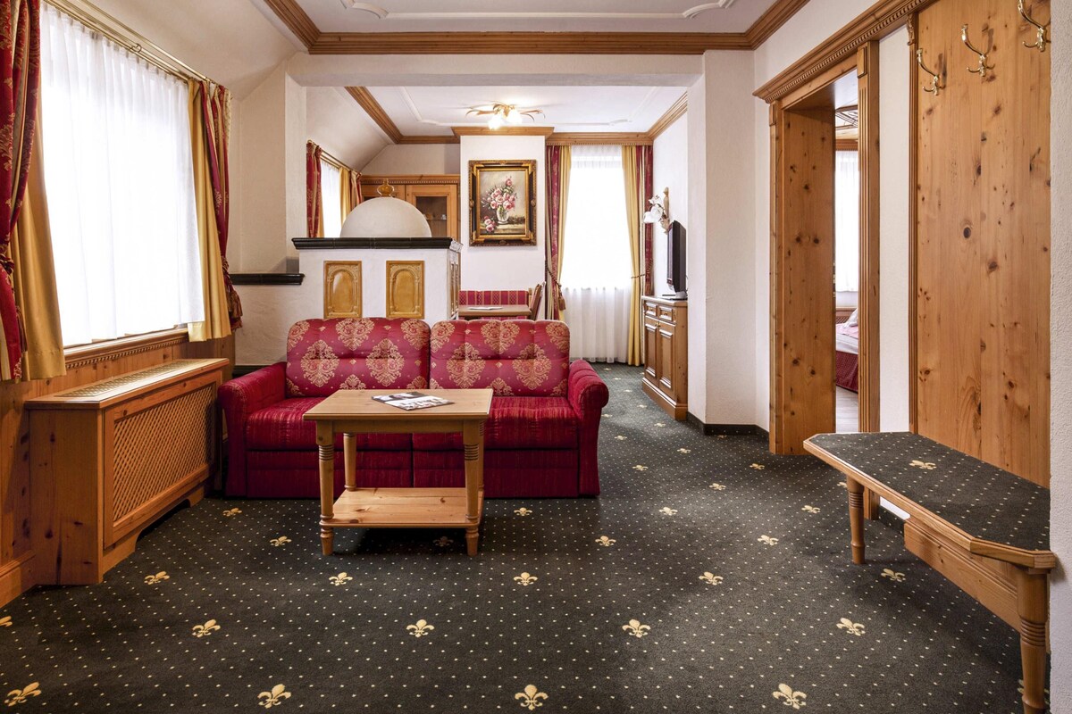 A room with a red sofa, a wooden table, and a bench. There is a wooden cabinet and a mirror on the wall.