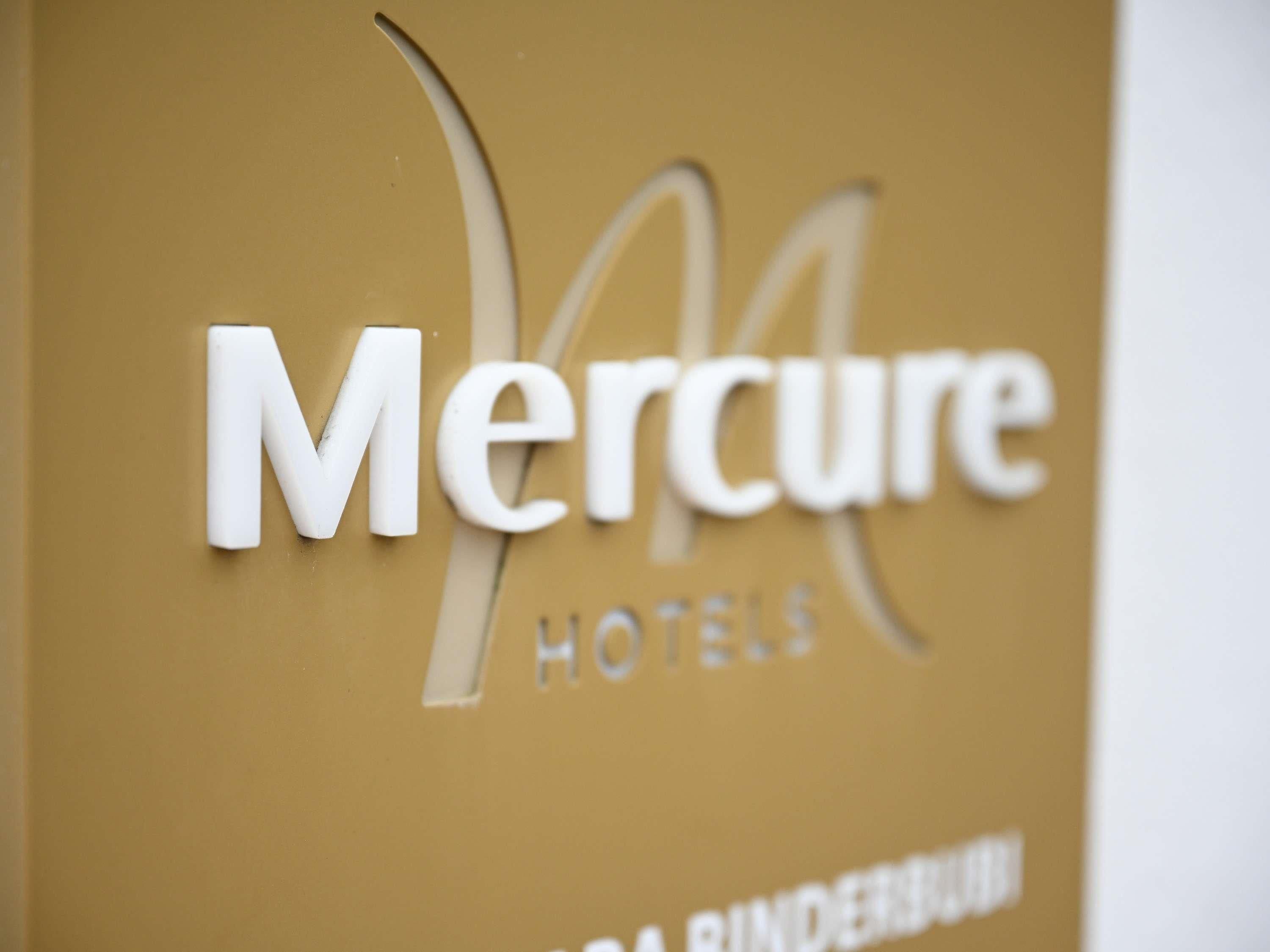 Primer plano del logotipo de Mercure Hotels sobre una pared color beige.