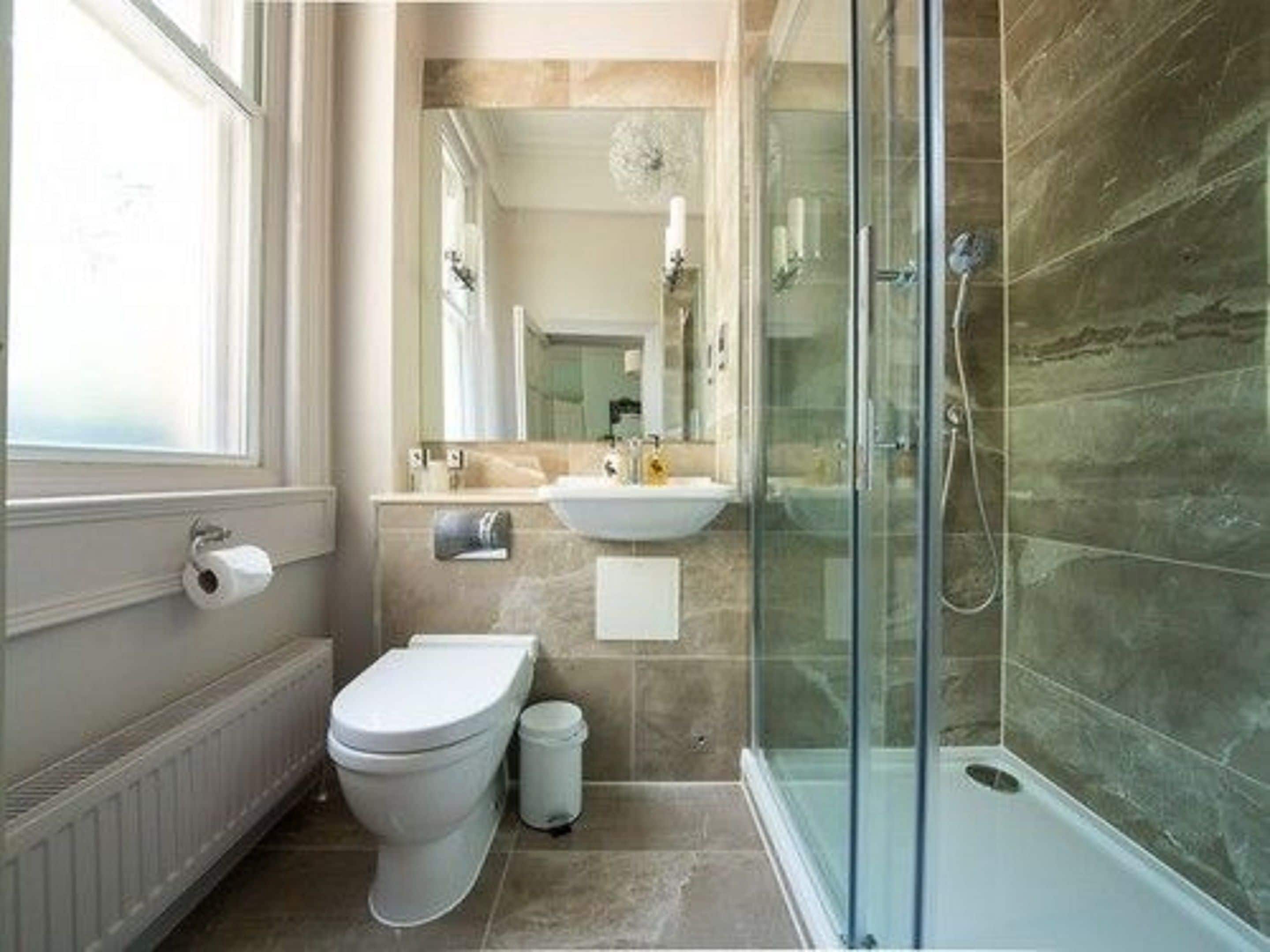 Un baño con inodoro, lavamanos y cabina de ducha de vidrio.