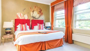 Un dormitorio con una cama grande, dos mesitas de noche, un mural en la pared y una ventana con cortinas.