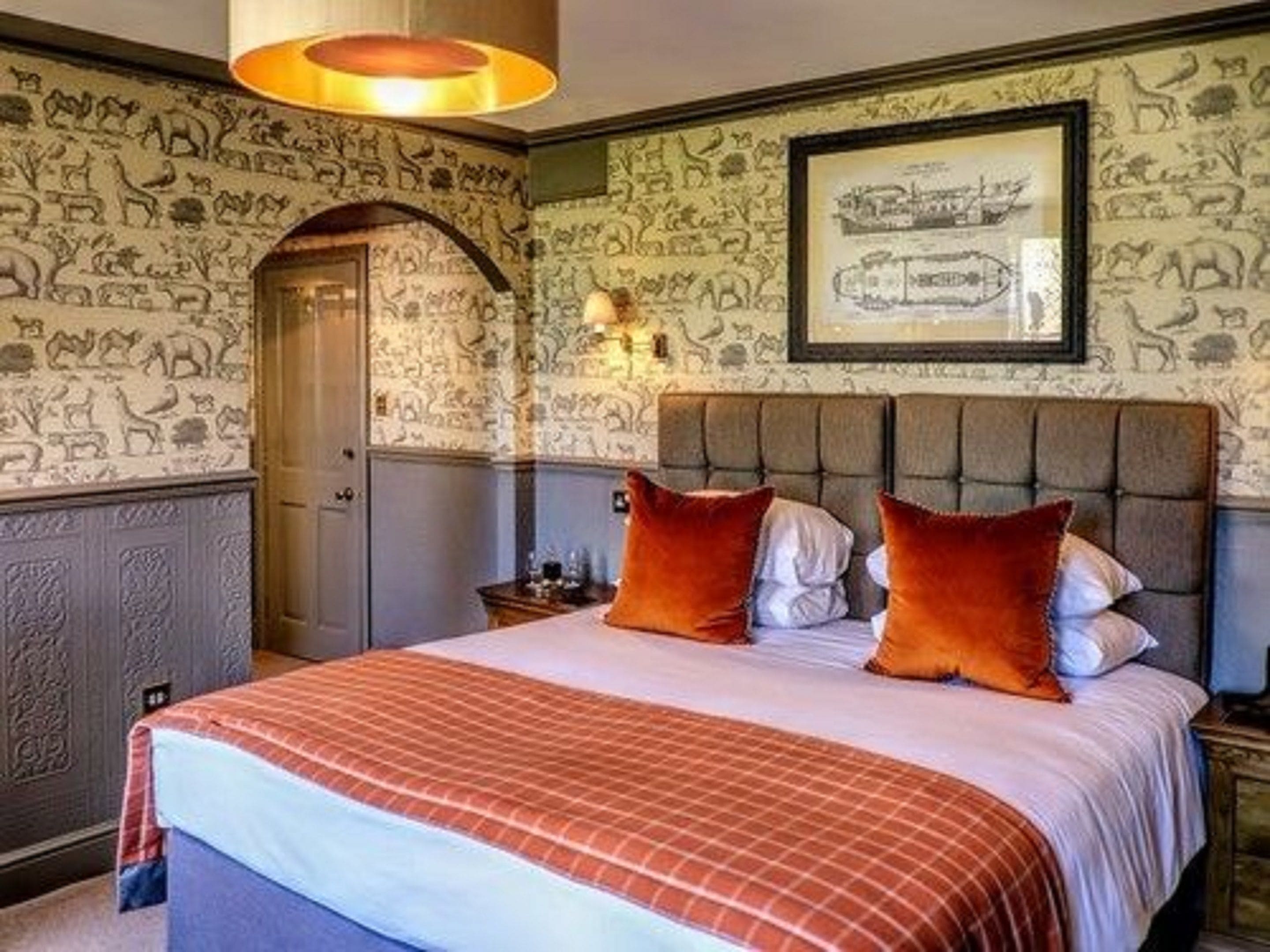 A bedroom with a large bed, a headboard, and a wall with animal illustrations.