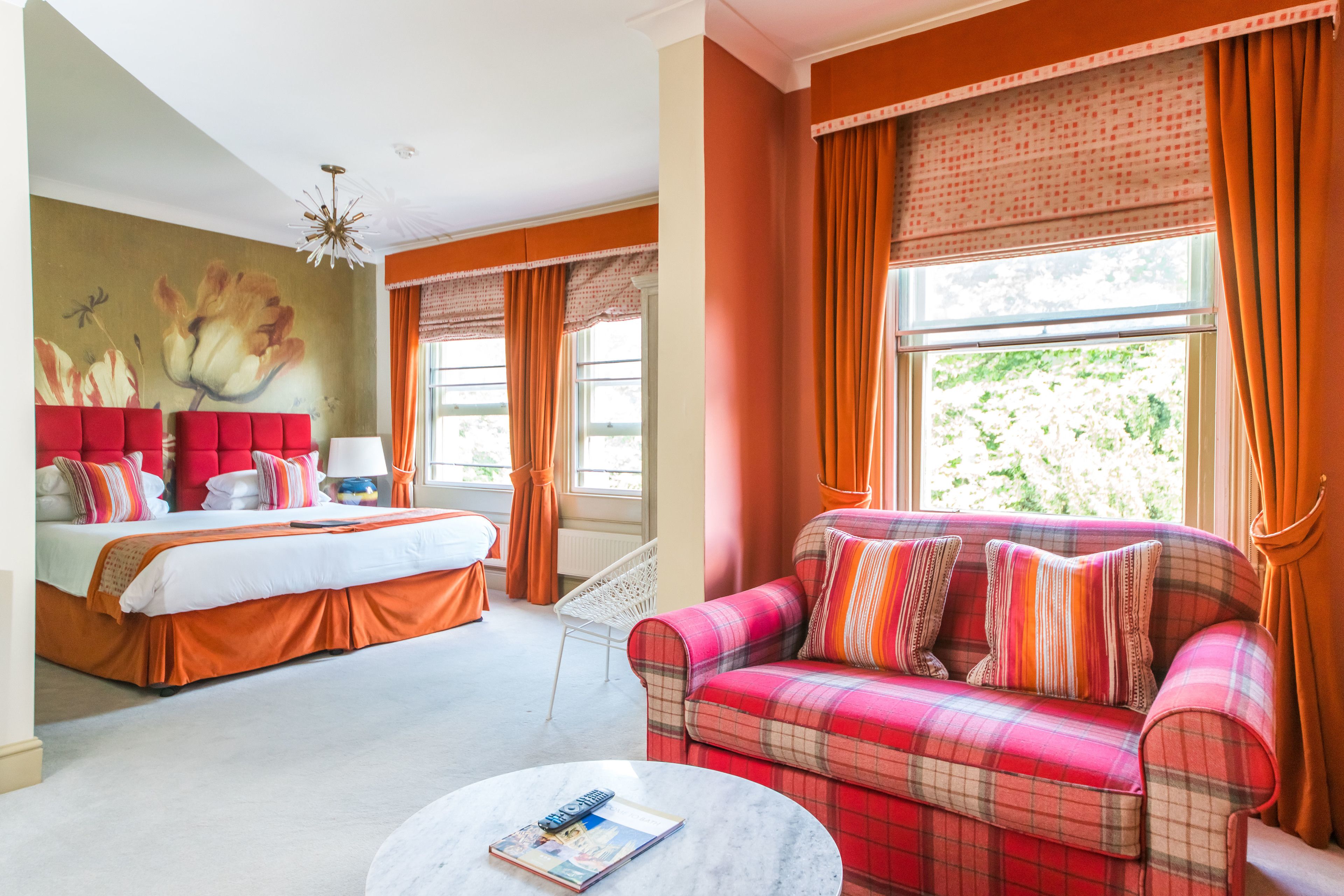 Ein Hotelzimmer mit Bett, Schlafsofa, rundem Couchtisch und einem Fenster mit Vorhängen.