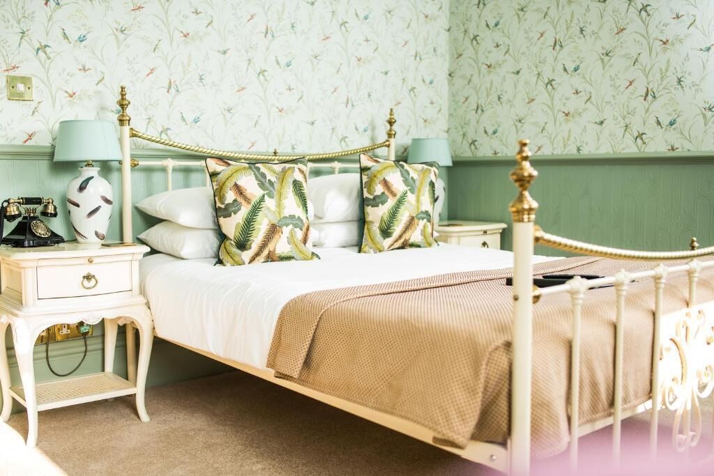 A bedroom with a bed, nightstands, a lamp, and a telephone.