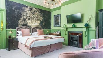 Um quarto com uma cama grande, televisão, lareira e uma parede verde.
