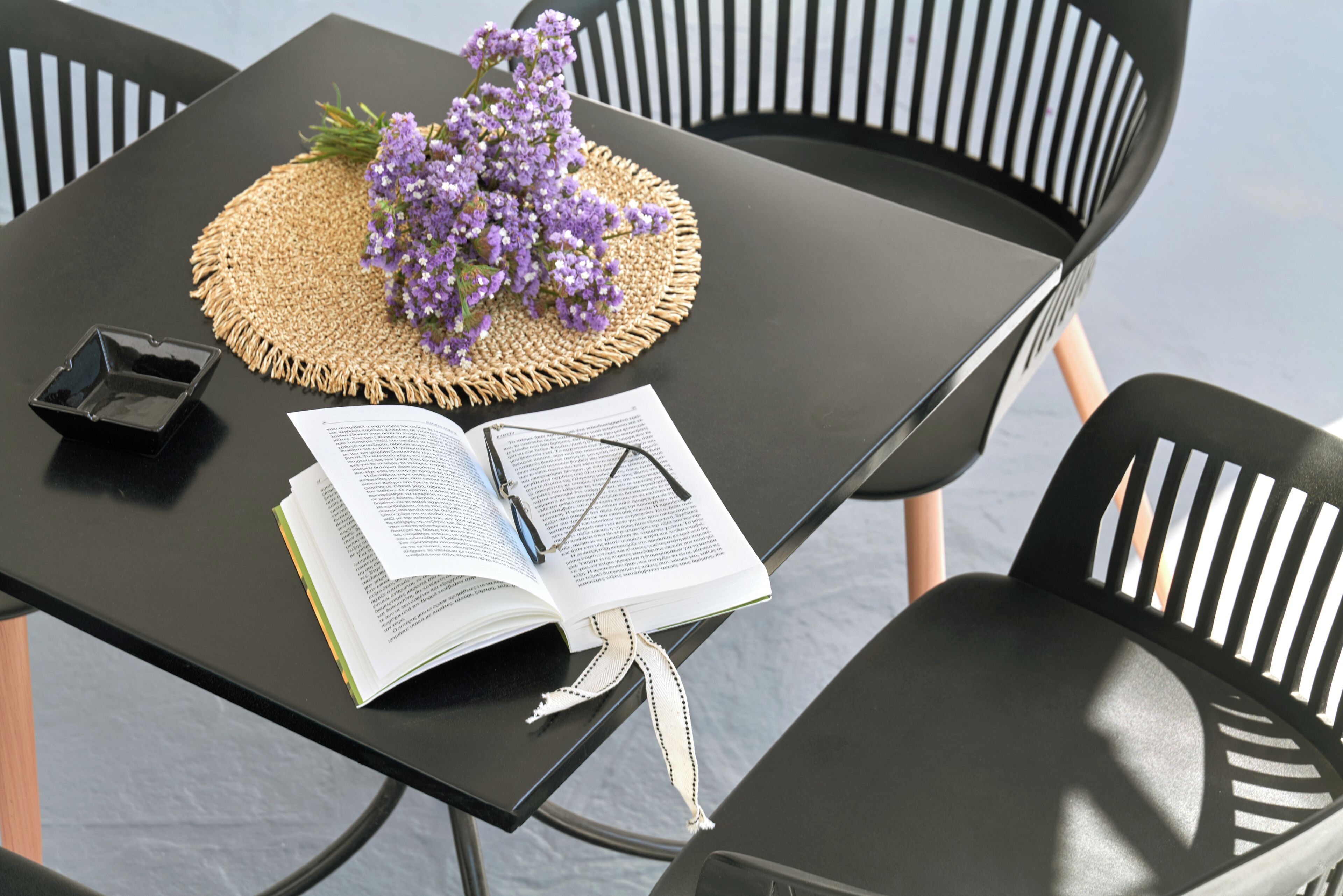 A table with an open book, a pair of glasses, and a small black object.