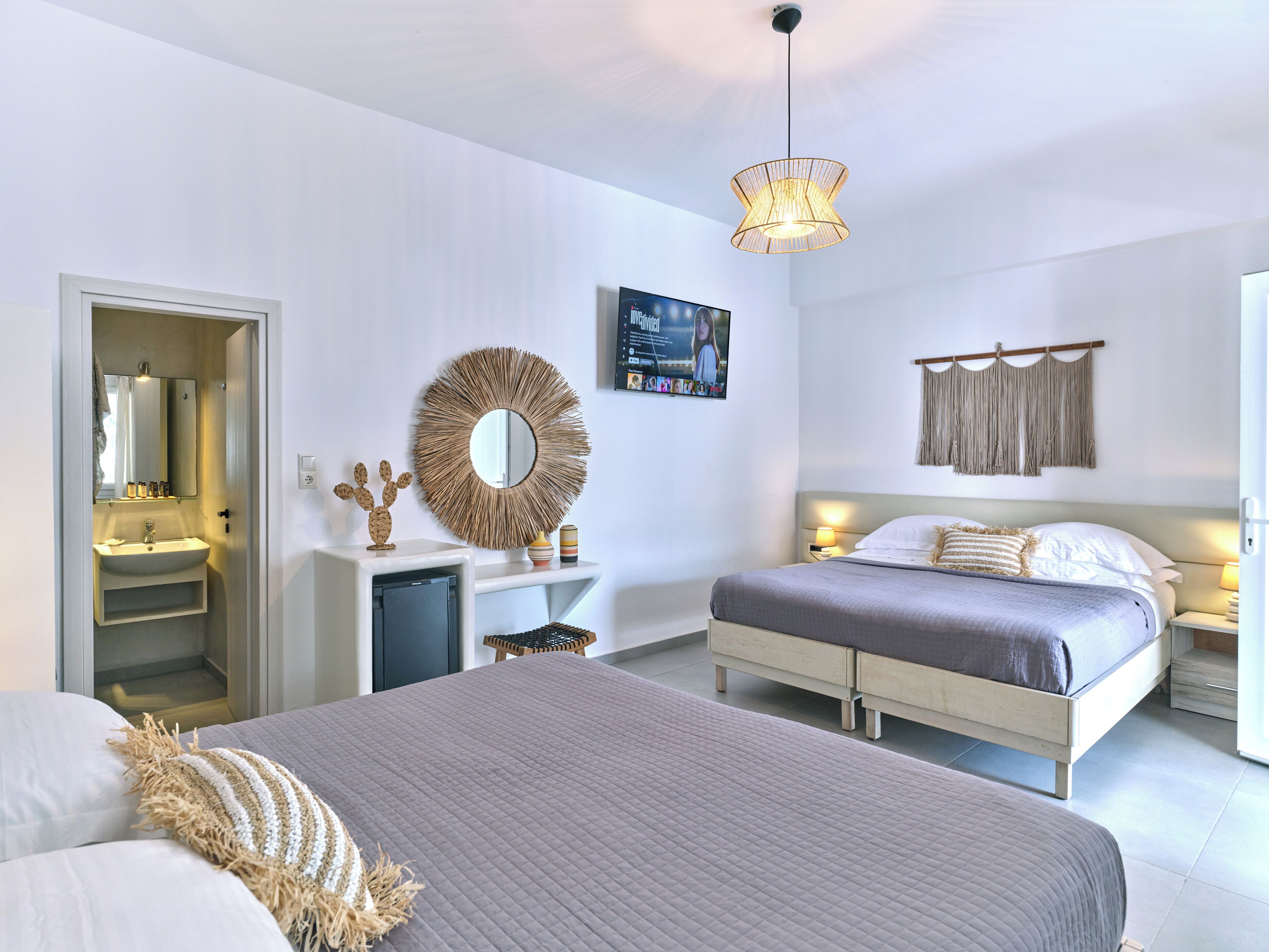 Un dormitorio moderno con una cama grande, mesitas de noche, un espejo y una lámpara fijada a la pared.