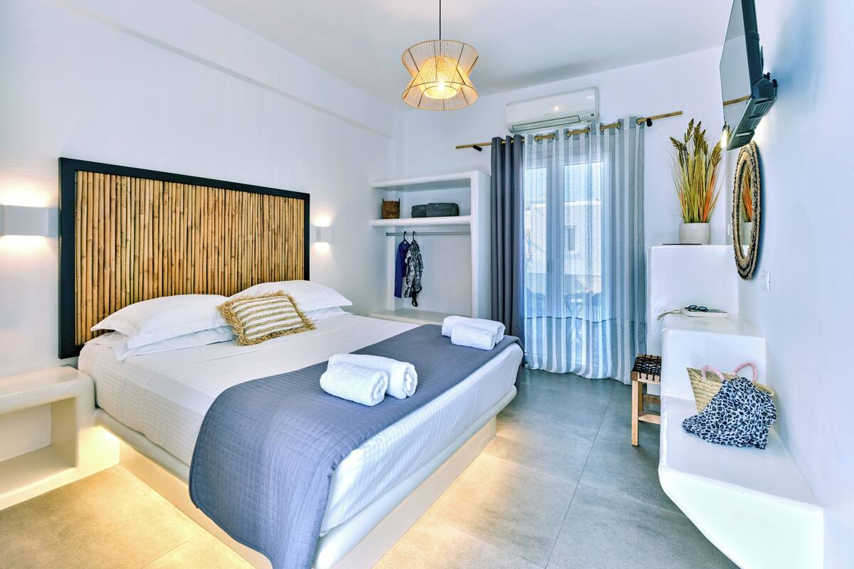 Une chambre à coucher moderne avec un grand lit, des tables de chevet, une armoire, un miroir et un luminaire au plafond.