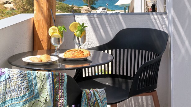 Un balcón con una mesa, dos sillas y vista al mar.