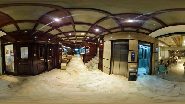 A spacious corridor with a curved ceiling, a central elevator, and a seating area with chairs and tables. - Hotel Posadas (Posadas)